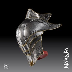 May include: A silver helmet with gold detailing and floral patterns, possibly from a fantasy film. The helmet has a curved shape, a red base, and is set against a dark backdrop. The text "The Chronicles of Narnia" is visible.