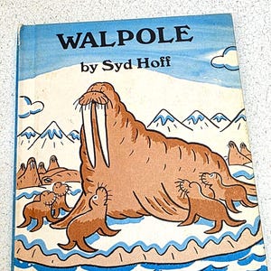 Puede incluir: Un libro infantil vintage titulado "WALPOLE" de Syd Hoff. La portada presenta una gran morsa de dibujos animados con largos colmillos y varias focas en un paisaje nevado con montañas y agua azul. El libro forma parte de la serie "An Early I Can Read Book".