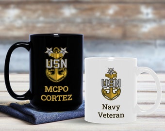 May include: Two ceramic coffee mugs with a gold anchor and the letters USN. The black mug has the text "MCPO CORTEZ" and the white mug has the text "Navy Veteran".