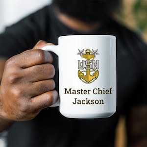 May include: White ceramic coffee mug with a gold anchor and stars design. The text "USN Master Chief Jackson" is printed on the mug.