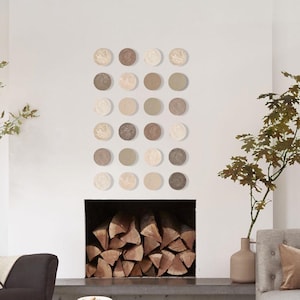 May include: A contemporary living room scene with a grey sofa, a black armchair, and a white coffee table. The room includes a fireplace with logs, decorative wall art, and natural wood elements, creating a comfortable ambience.