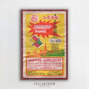 Könnte beinhalten: Vintage Feuerwerkskörper-Verpackung "Thunder Bomb" mit rotem und gelbem Design. Das Etikett zeigt chinesische Schriftzeichen, einen roten Stern und Illustrationen von Feuerwerkskörpern. Text: "Vorsicht - Explosiv".