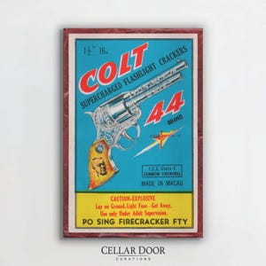 May include: Vintage Colt 44 brand firecracker box with a blue background and a revolver illustration. The box features the text "COLT SUPERCHARGED FLASHLIGHT CRACKERS" and "CAUTION-EXPLOSIVE". The box measures 3.8 cm.