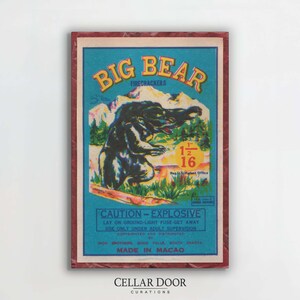 Könnte beinhalten: Vintage Big Bear Feuerwerkschachtel mit einer Illustration eines schwarzen Bären auf blauem Hintergrund. Der Text lautet "BIG BEAR FIRECRACKERS" in Gelb, mit Sicherheitshinweisen und Maßen. Die Schachtel ist mit einem roten Rahmen versehen.
