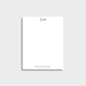 May include: A white card featuring the initials "SJM" in black at the top. The name "SHAWN MICHEAL JAMES" is printed in black below, underlined with a thin black line. The card is set against a light grey background.