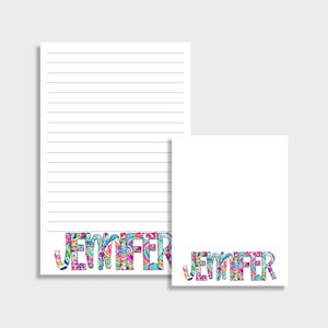 Puede incluir: Dos blocs de notas blancos, uno rayado y otro en blanco, con el nombre "JENNIFER" en letras coloridas y estampadas en la parte inferior. Las letras presentan una mezcla de diseños rosas, azules, verdes y amarillos.