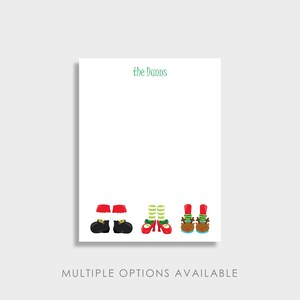 May include: White stationery with green text that reads "the Danns." The bottom of the stationery features illustrations of Christmas elf and Santa Claus feet. The text "MULTIPLE OPTIONS AVAILABLE" is at the bottom.