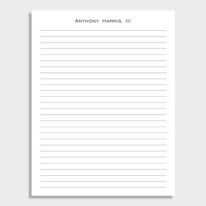May include: A white notepad with horizontal grey lines and the text "ANTHONY HARRIS, III" at the top. The notepad is designed for writing. The background is plain white.