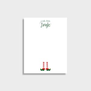 May include: A white notepad with the text "a note from Jingle" in green script. The bottom of the notepad features a graphic of elf legs with red and white striped socks and green shoes.