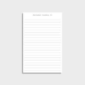 May include: A white notepad with horizontal gray lines and the text "ANTHONY HARRIS, III" at the top. The notepad is rectangular and sits on a white surface.