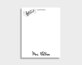 Op de afbeelding: Witte notitieblok met zwarte muzieknoten en de tekst "A NOTE FROM" bovenaan. De naam "Mrs. Hullum" staat in cursief onderaan. Het notitieblok is rechthoekig.