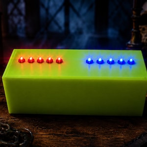 May include: A rectangular lime green box featuring two rows of five small circular lights on the top surface. The left row consists of five glowing red lights, while the right row consists of five glowing blue lights, all set into the flat top.