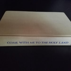 May include: A hardcover book with a light tan cover. The title "COME WITH ME TO THE HOLY LAND" is printed in dark blue on the spine. The book is a complete edition by Judson and Patterson.