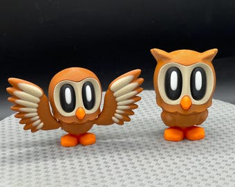 May include: Two brown owl figurines with white eyes. One owl has outstretched wings and the other is standing upright.