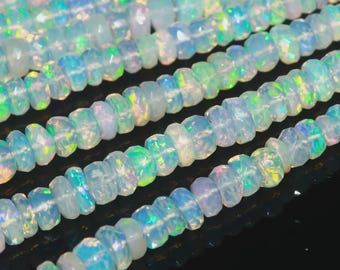 May include: Strands of faceted opal beads. The beads are a milky white color with iridescent flashes of blue, green, and yellow. The beads are strung together, creating a shimmering effect.
