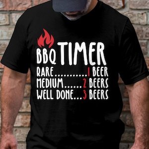 May include: Black t-shirt with white text that reads "BBQ TIMER" and a list of doneness levels for meat with corresponding beer counts: "Rare... 1 Beer", "Medium... 2 Beers", "Well Done... 3 Beers".