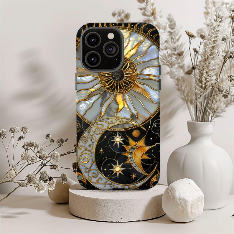 May include: Black phone case featuring a celestial design with a sun, moon, and stars. The sun is gold and yellow, the moon is gold, and the stars are white. The case has a glossy finish.