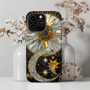 May include: A black phone case featuring a celestial design with a sun, moon, and stars. The sun is gold and white, the moon is silver, and the stars are gold. The case has a decorative, stained-glass style.