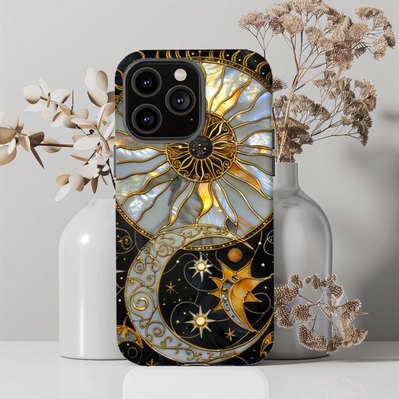 May include: A black phone case featuring a celestial design with a sun, moon, and stars. The sun is gold and white, the moon is silver, and the stars are gold. The case has a decorative, stained-glass style.