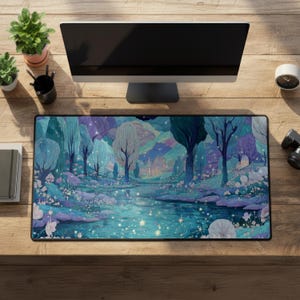 以下が含まれることがあります： 青、紫、白の色合いで川、木、城を描いた、穏やかな風景が特徴の長方形のデスクマット。 デスクマットは木製の机の上に置かれ、コンピューターモニター、植物、その他のオフィス用品が置かれています。