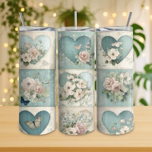 Peut inclure: Trois gobelets en acier inoxydable avec couvercles et pailles. Chaque gobelet présente un motif répété de cœur turquoise avec des arrangements floraux et des papillons. Les fleurs sont dans des tons de rose et de blanc, sur fond crème.