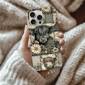 Puede incluir: Una funda de teléfono con un diseño de vaca de las Tierras Altas. El diseño presenta un patrón de patchwork con margaritas y un cuadrado a cuadros en blanco y negro. La vaca es negra y gris con cuernos. La funda se sostiene en una mano.