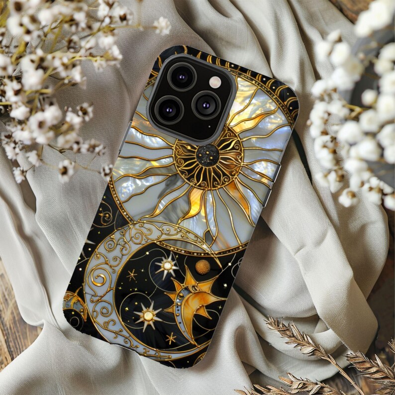 May include: A black and gold celestial-themed phone case featuring a sun, moon, and stars design. The case has a pearlescent background with gold accents and a black border. The phone case is designed to fit a smartphone.