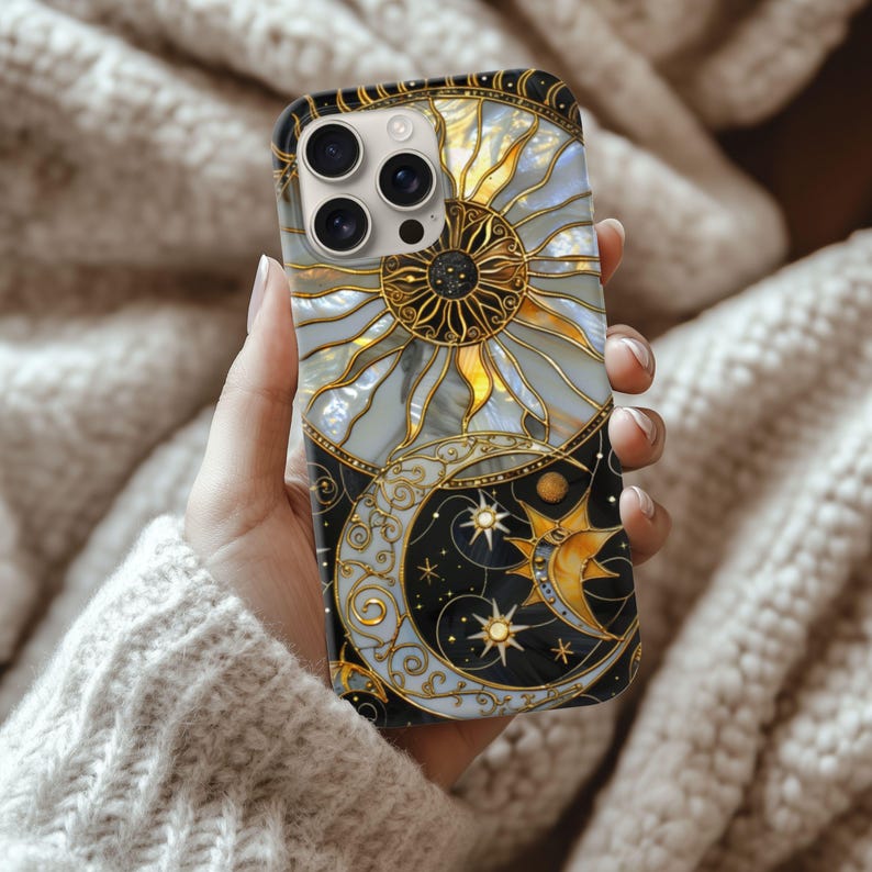May include: A decorative phone case featuring a celestial design with a sun, moon, and stars. The case has a gold and black border, with a detailed sun design in the upper half and a crescent moon and stars in the lower half.