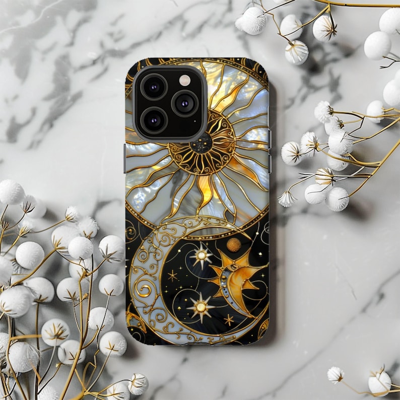 May include: A decorative phone case featuring a celestial design. The case showcases a sun and moon motif with gold accents, set against a black and white background. The sun is golden with white rays, and the moon is a crescent shape with stars.