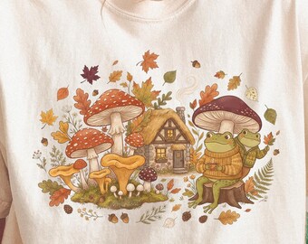 Maglietta con accogliente cottage autunnale, rane e funghi / Illustrazione di foglie autunnali e bosco