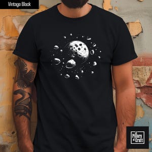 May include: Black t-shirt with a white graphic of a moon surrounded by asteroids. The shirt has the text "Vintage Black" at the top left and the "Pillars of Craft" logo at the bottom right.