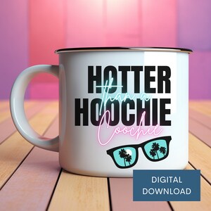 K&ouml;nnte beinhalten: Eine wei&szlig;e Emailletasse mit einer schwarzen, neongelben und blauen Grafik, auf der "Hotter than a Hoochie Coochie" steht, sowie Sonnenbrillen mit Palmen, die sich in den Gl&auml;sern spiegeln. Die Tasse steht auf einer Holzoberfl&auml;che.
