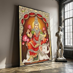 May include: Large framed artwork depicting a Hindu deity, seated on a white elephant. The artwork features vibrant colors, including red, green, and gold, with intricate details and floral motifs. The deity holds lotus flowers, set against a warm, golden background.