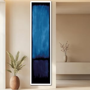 May include: A framed abstract painting with a blue and black colour scheme. The painting is in a white frame and is hanging on a beige wall.