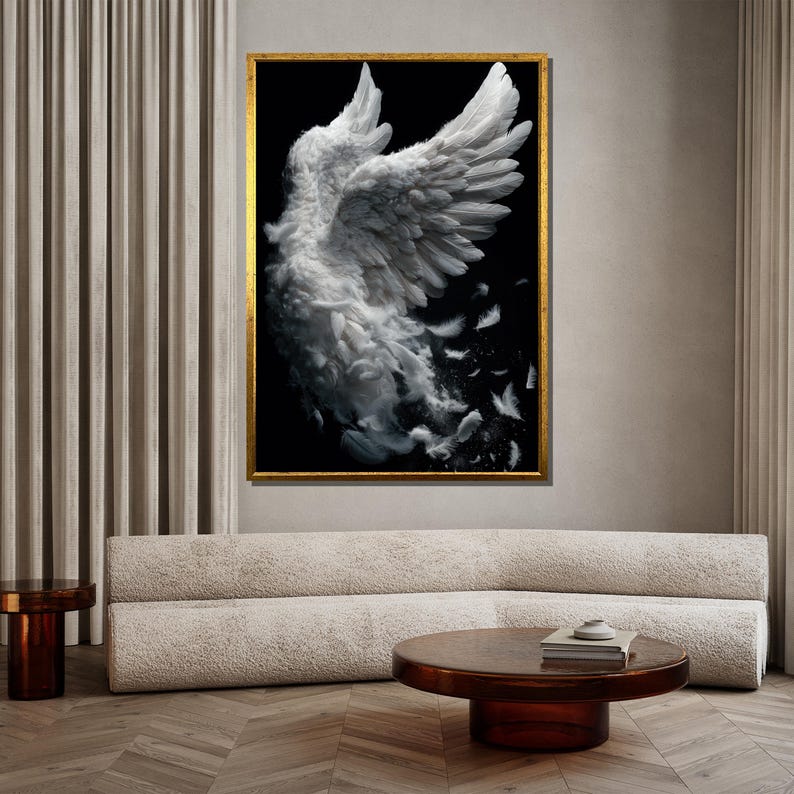 May include: A framed art print featuring a pair of white angel wings against a black background. The wings are detailed with individual feathers, some of which appear to be falling away. The frame is gold, and the artwork is displayed in a modern living room setting.