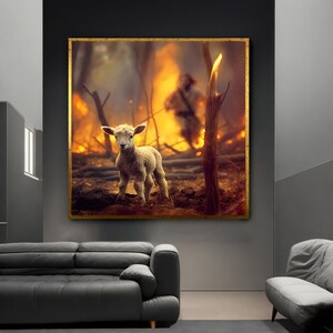 May include: A small, white lamb stands in a field of burnt trees and brush. The lamb is looking directly at the camera. The background is a hazy orange and yellow, suggesting a recent fire.
