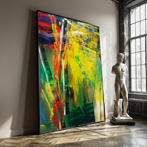 May include: Large framed abstract painting with a black border. The artwork features bold strokes of red, yellow, green, and blue, creating a vibrant and energetic composition. The painting leans against a wall in a room with a statue.