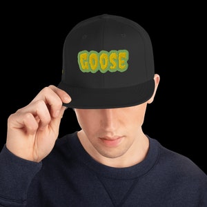 May include: A black fitted baseball cap with a green and yellow embroidered "GOOSE" logo.