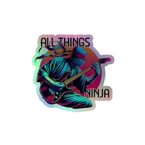 Puede incluir: Una pegatina con un ninja tocando una guitarra eléctrica con el texto "All Things Ninja" en letras negras sobre un fondo holográfico.