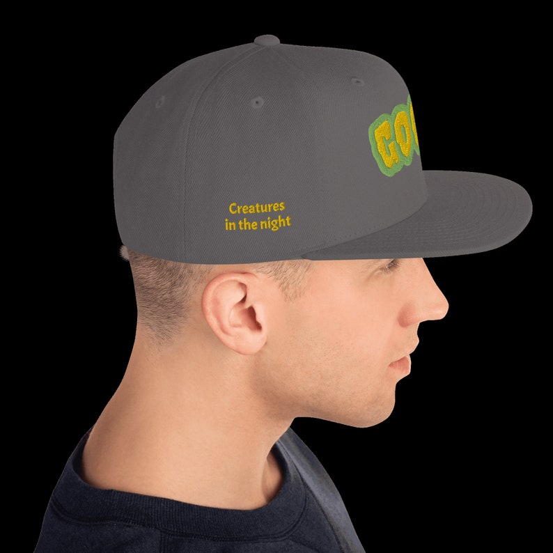 May include: A gray baseball cap with a green and yellow embroidered logo that says "GO!" and the text "Creatures in the night" in yellow.