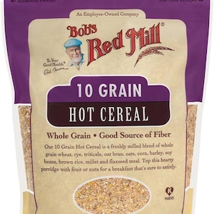 May include: A packet of Bob's Red Mill 10 Grain Hot Cereal. The packaging is tan with a purple top and bottom. The text includes "Whole Grain" and "Good Source of Fiber". The net weight is 709g.