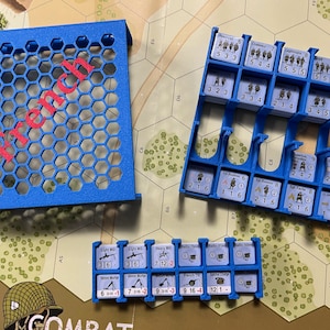 Può includere: Contenitori di stoccaggio in plastica blu per pezzi di gioco. I contenitori sono etichettati con numeri e testo, tra cui "French".