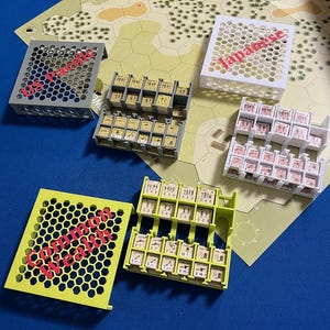 Peut inclure: Un jeu de guerre de table avec divers composants. L'image montre plusieurs plateaux avec des pièces de jeu, y compris des unités et des marqueurs. Les plateaux sont de différentes couleurs, dont le gris, le blanc et le vert. Le texte "Japanese" et "Commonwealth" est visible sur certains plateaux.