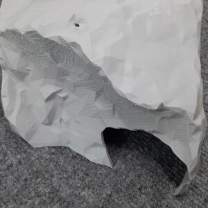May include: A white 3D printed rock with a cave opening. The rock has a textured surface and appears to be made of plaster or resin.