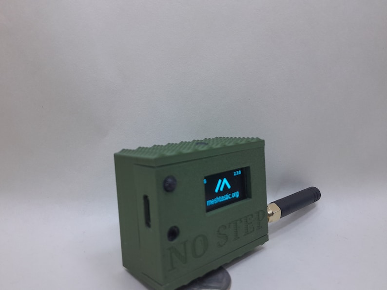 May include: A green, rectangular box with a small screen displaying a blue arrow and the text "mechcastic.org". The box has a black antenna and the text "NO STEP" printed on the front.