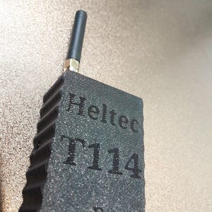 May include: A dark gray Heltec T114 device with a textured surface and a black antenna. The device has the text "Heltec T114" printed on its surface. The antenna is attached to the top of the device.