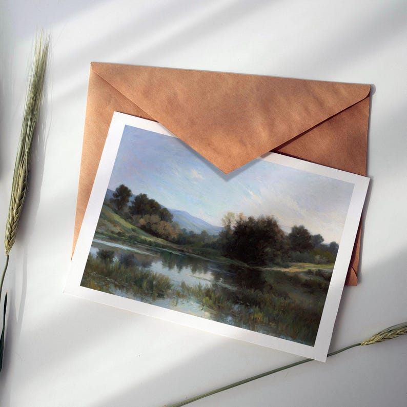 May include: A brown envelope with a white card inside. The card features a painting of a lake surrounded by trees and hills. The sky is a light blue with some clouds.