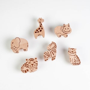 Könnte beinhalten: Sechs Holzfiguren von Tieren, darunter eine Giraffe, ein Flusspferd, ein Elefant, ein Zebra, ein Tiger und ein Leopard. Die Figuren sind alle aus hellem braunem Holz geschnitzt und haben detaillierte schwarz-weiße Markierungen.