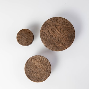 May include: Three wooden wall hooks in different sizes. The hooks are round and have a dark brown finish.