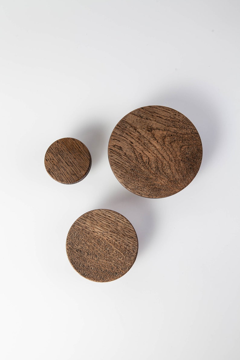 May include: Three wooden wall hooks in different sizes. The hooks are round and have a dark brown finish.